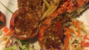 A plate with two cooked lobsters, a side of French fries, and a mixed vegetable salad. - Sana's Beach Guesthouse and Restaurant (Negombo)