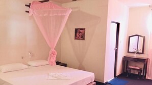 A bedroom with a bed, a bedside table, a mirror, and a picture on the wall. - Sana's Beach Guesthouse and Restaurant (Negombo)