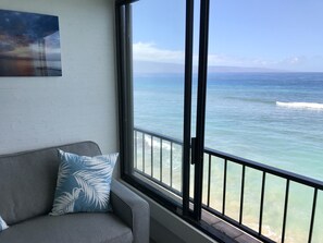 A room with a large window offering a view of the ocean.