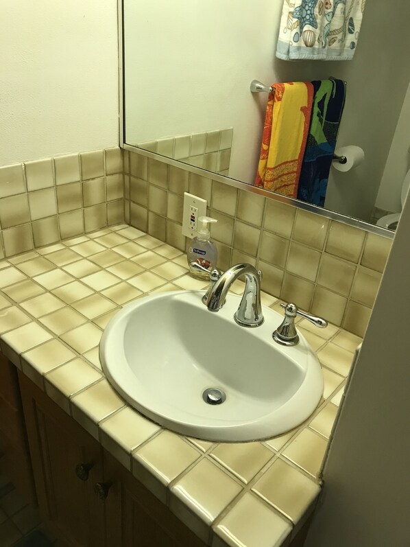 A bathroom with a white sink, a mirror, and a hand soap dispenser.