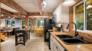 Una cocina amplia con vigas de madera, un ventanal grande y un comedor con mobiliario de madera.