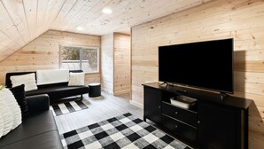 Una sala de estar moderna con un sofá negro, un mueble negro para televisión y una alfombra a cuadros.