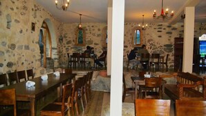 Ein Restaurant mit Steinsäulen, Holztischen und -stühlen.