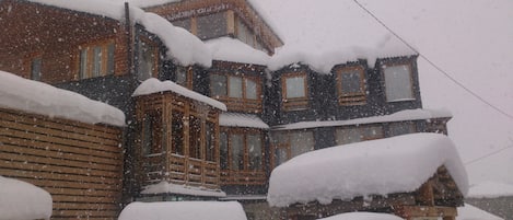 Una cabaña de madera con varias ventanas y un tejado cubierto de nieve.