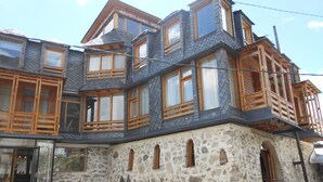 Ein mehrstöckiges Steinhaus mit hölzernen Balkonen und großen Fenstern.