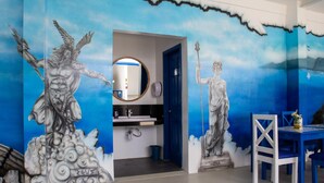 A room with a mural of mythological figures, a sink, and a table with chairs. - Skytel Palawan (Puerto Princesa)