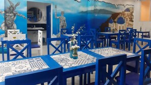 A dining area with blue chairs and tables, decorated with white and blue patterned tablecloths and a vase with flowers. - Skytel Palawan (Puerto Princesa)