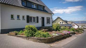 Ein zweistöckiges Haus mit Garten, einer gepflasterten Auffahrt und einem Windrad im Hintergrund.