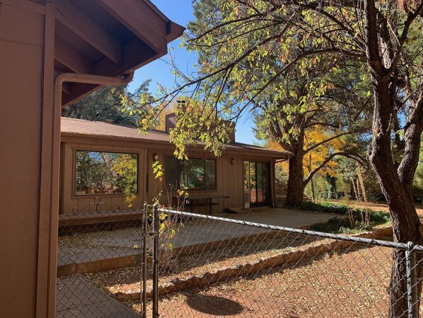 A modern building with large windows, a covered patio, and a fenced outdoor area.