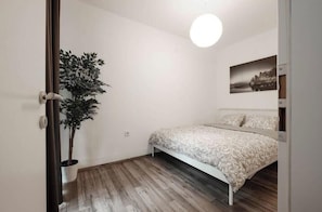 Ein Schlafzimmer mit einem Bett, einer Topfpflanze und einem Wandbild.
