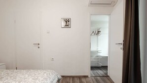 Une chambre à coucher comprenant un lit, une armoire et une porte donnant sur une salle de bain.