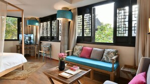 Une chambre d’hôtel moderne dotée d’une grande fenêtre, d’un canapé, d’un lit, d’un bureau et d’une chaise.