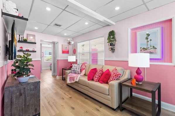 Een woonkamer met een beige bank, roze wanden en een houten salontafel.