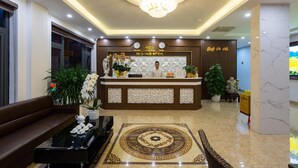 A hotel reception area with a modern design, featuring a reception desk, a chandelier, and a decorative floor pattern. - Victoria Hotel Ninh Binh (Hoa Lu)