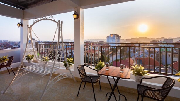 A balcony with a swing chair, a table with chairs, and potted plants. - Victoria Hotel Ninh Binh (Hoa Lu)