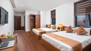 A hotel room with two beds, a desk with a laptop, and a TV mounted on the wall. - Victoria Hotel Ninh Binh (Hoa Lu)