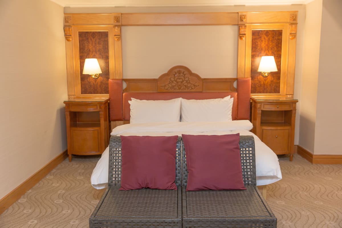 A hotel room with a large bed, two nightstands, and a small seating area.