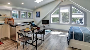 A compact kitchen with modern appliances, a dining area with a table and chairs, and a bedroom with a bed. - Hawthorne Urban Loft Private ADU with Parking & AC (Portland)