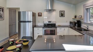 A modern kitchen with stainless steel appliances, a central island, and a window providing natural light. - Hawthorne Urban Loft Private ADU with Parking & AC (Portland)