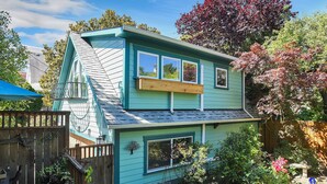A two-story house with a steeply pitched roof, a front porch, and a small deck. - Hawthorne Urban Loft Private ADU with Parking & AC (Portland)