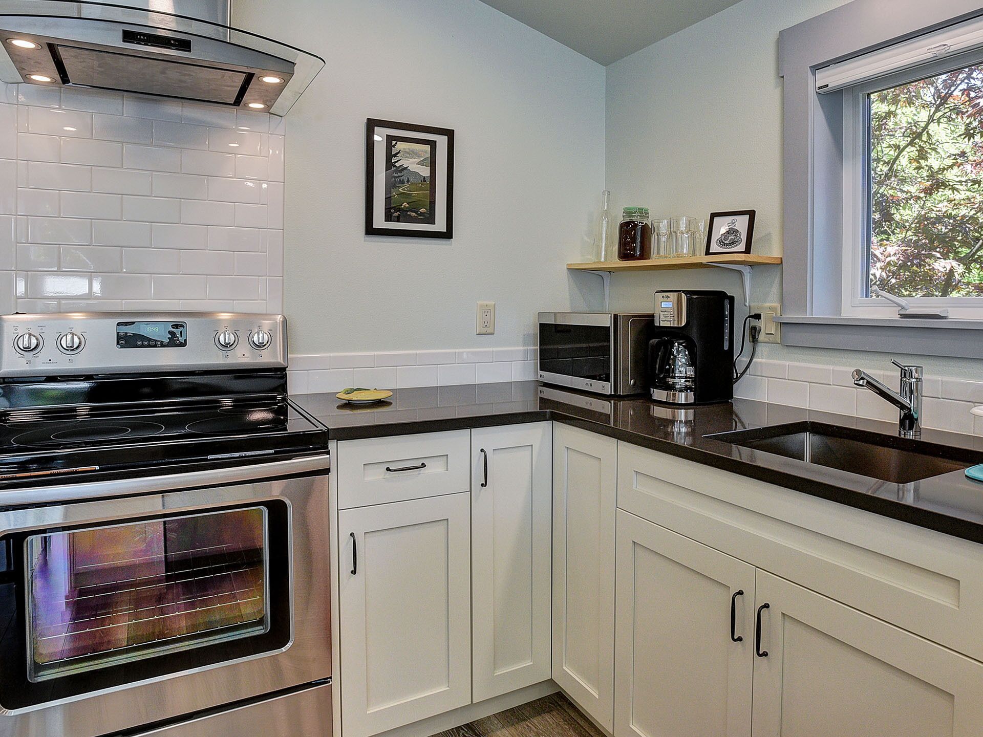 A modern kitchen with stainless steel appliances, white cabinetry, and a window providing natural light.