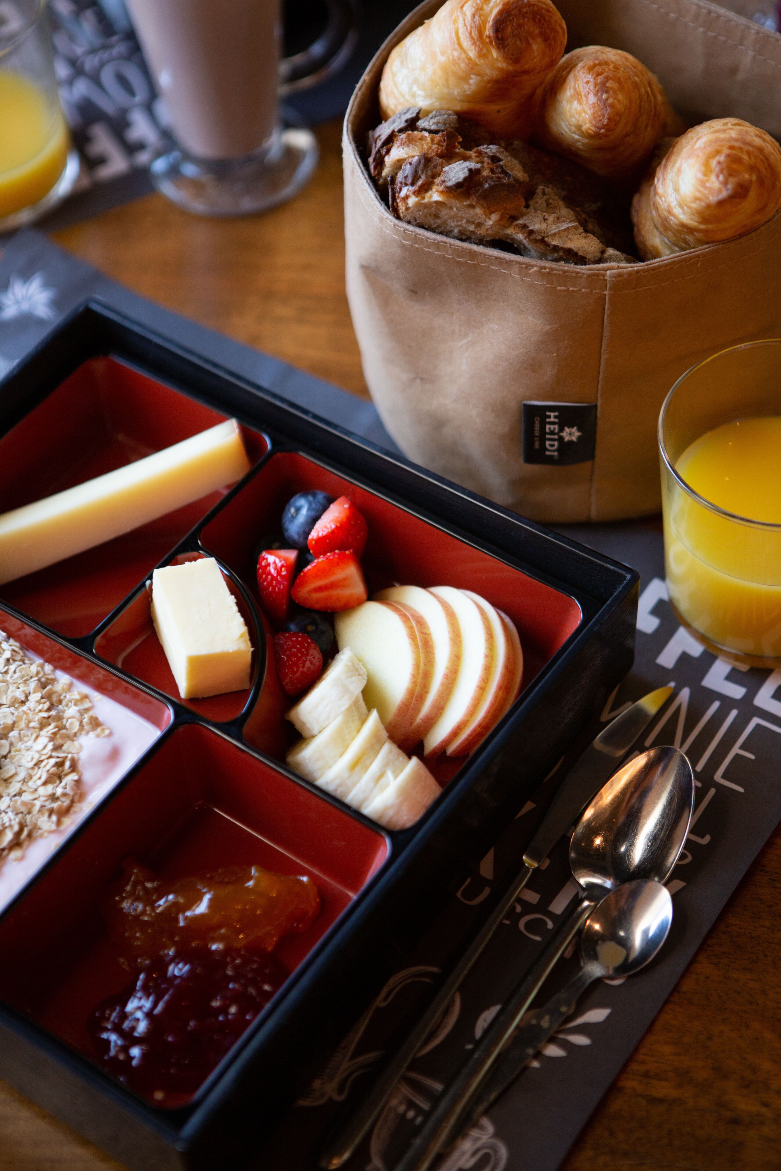 A meal tray with compartments containing various foods, a glass of orange juice, and cutlery.