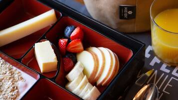 A meal tray with compartments containing various foods, a glass of orange juice, and cutlery.