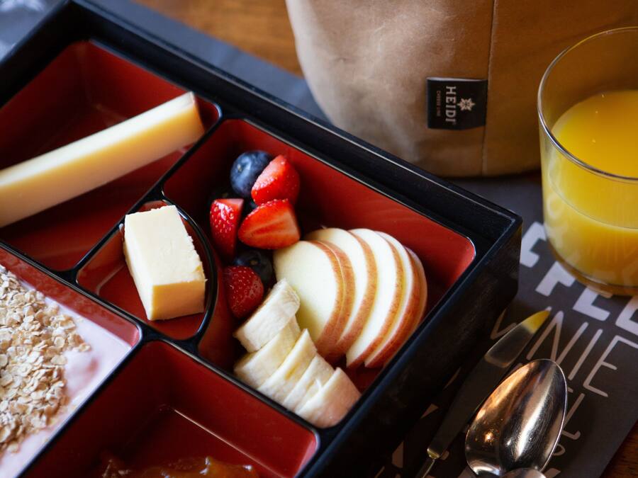 A meal tray with compartments containing various foods, a glass of orange juice, and cutlery.