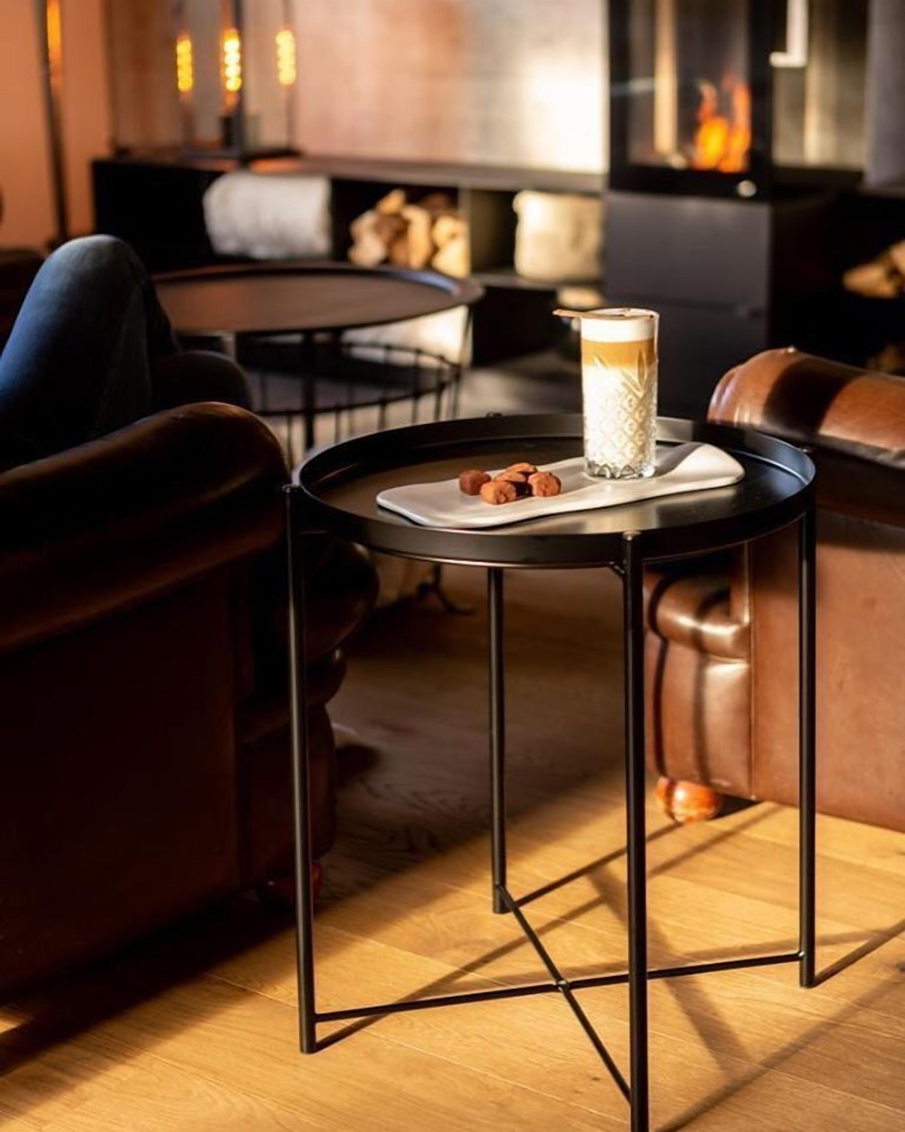 Un rincón acogedor con una mesa redonda, una bebida en un vaso y un plato de galletas.