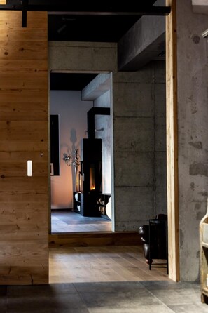 A modern interior with a wooden wall, a fireplace, and a black leather sofa. - Hotel de l'Ours Preles (Plateau de Diesse)