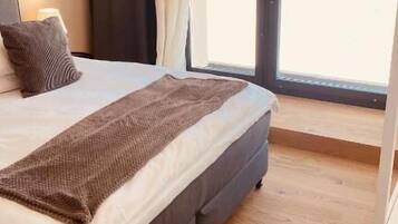 A bedroom with a large bed, a window with curtains, and a view of a snowy landscape.