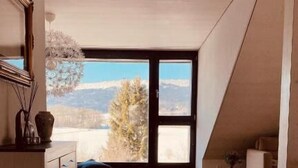 A spacious attic room with a large window offering a mountain view. - Hotel de l'Ours Preles (Plateau de Diesse)