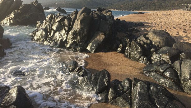Una costa rocosa con olas rompiendo sobre la arena.