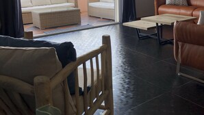 Una sala de estar con un sofá, un sillón, una mesa de centro y vistas al balcón exterior a través de una puerta de cristal.