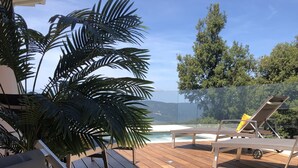 Una terraza de madera con sillones de descanso y una planta en maceta.