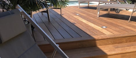 Una terraza de madera con sillones de descanso y una planta en maceta.