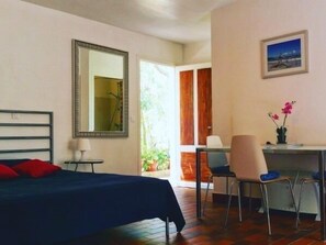 Ein Schlafzimmer mit Bett, Schreibtisch, Stuhl, Spiegel und Fenster.