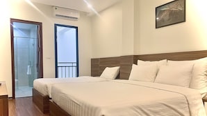 A hotel room with a large bed, a wooden headboard, a framed picture on the wall, and a door leading to a balcony. - Paragon House & Residence (Hanoi)