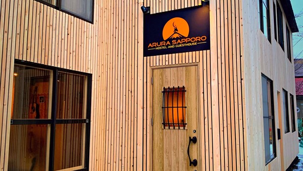 A wooden building with a sign reading "Arura Sapporo Hostel and Guesthouse." - Arura Sapporo - Hostel (Sapporo)