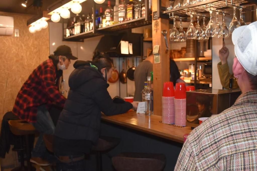 Un espace bar avec des tabourets, un comptoir et des étagères remplies de bouteilles et de verres.