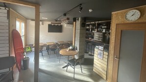 A cozy café with wooden furniture, a reception desk, and a clock on the wall. - Arura Sapporo - Hostel (Sapporo)