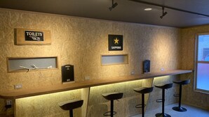 A bar area with stools, a sign for 'TOILETS', and a 'SAPPORO' sign on the wall. - Arura Sapporo - Hostel (Sapporo)