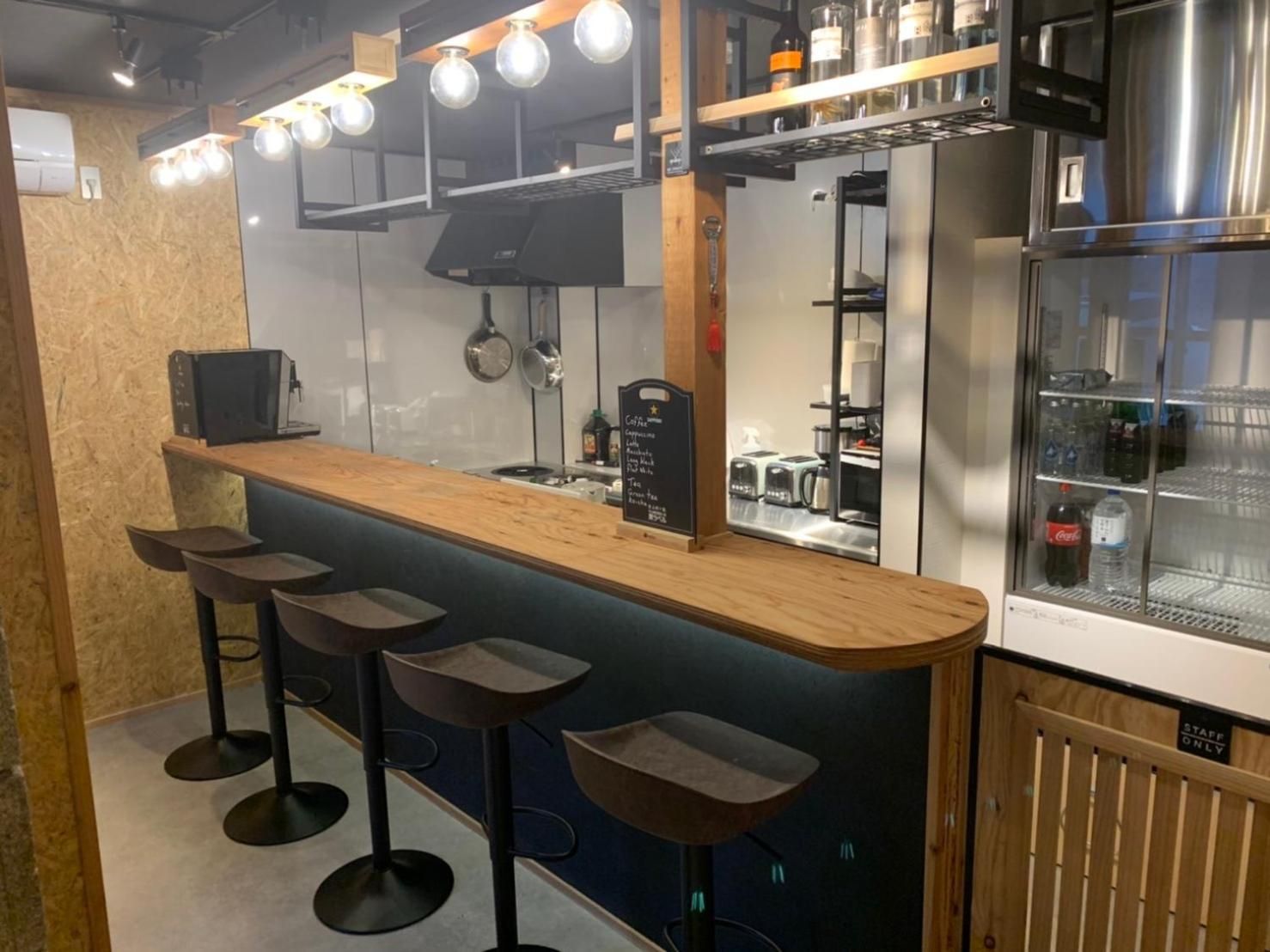 A bar area with a wooden counter, four stools, and a refrigerator stocked with beverages.