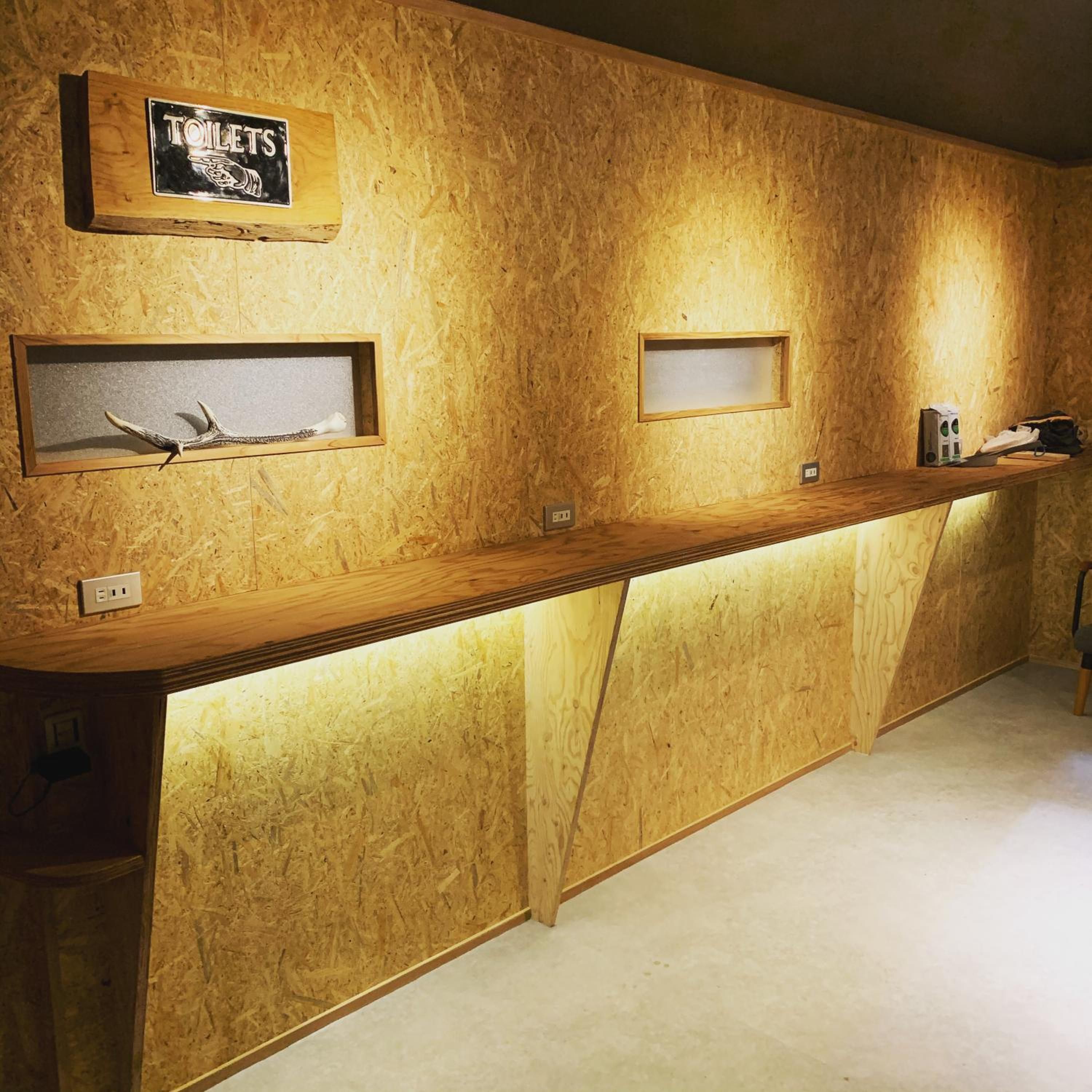 A reception desk with a wooden finish, a sign indicating the location of toilets, and two framed items on the wall.