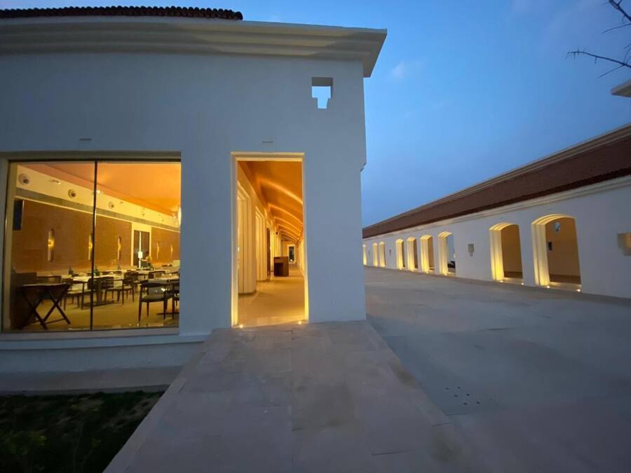 A hotel corridor with a dining area on the left and a series of arches on the right.