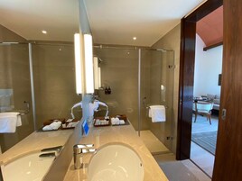 Un baño moderno con un espejo grande, una bañera y zona de ducha.
