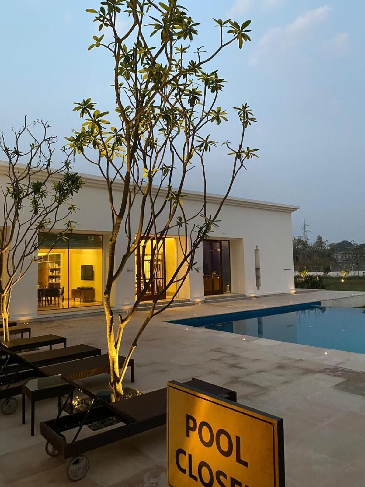 A modern house with a swimming pool, a 'POOL CLOSE' sign, and outdoor seating.