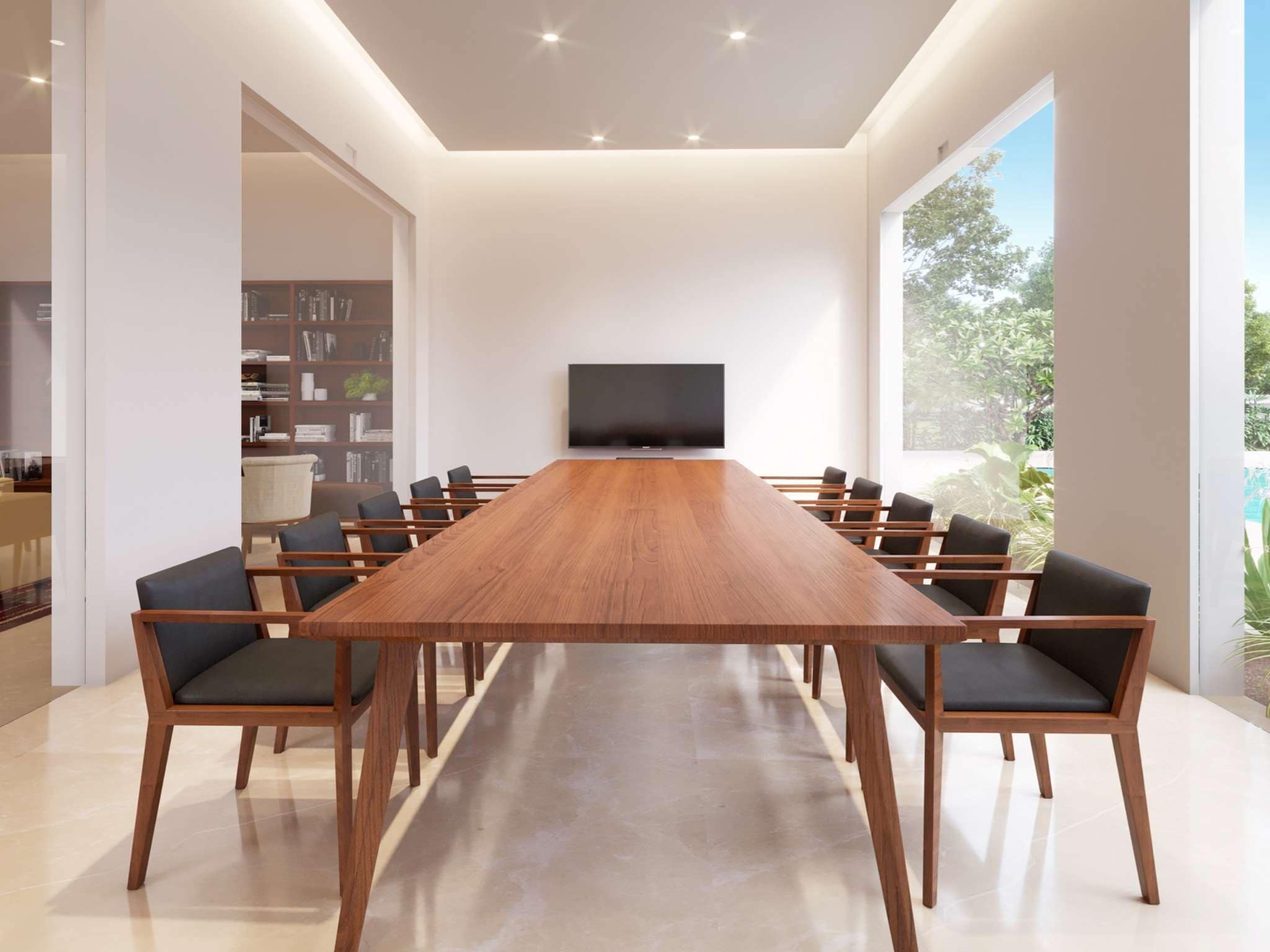 A modern meeting room with a long wooden table, black chairs, a flat-screen TV, and a bookshelf.