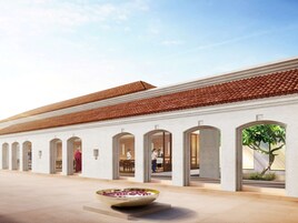 Un edificio con techo de tejas, arcos y un patio central con un arreglo floral.