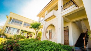 A two-story building with a balcony, a staircase, and a circular window.